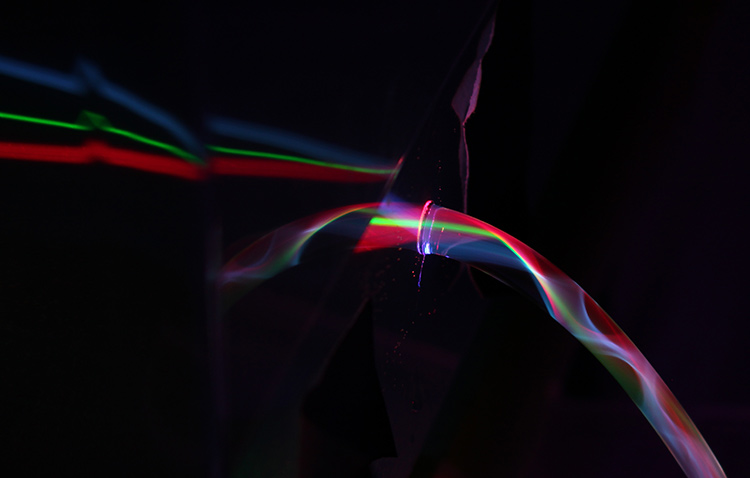 A multiplexing stream: The beams from three laser pointers of different wavelengths pass through a tank of water, and exit into a single water stream